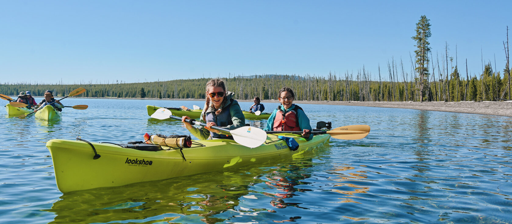 Two middle school girls smiling while sea kayaking on Yellowstone Lake.