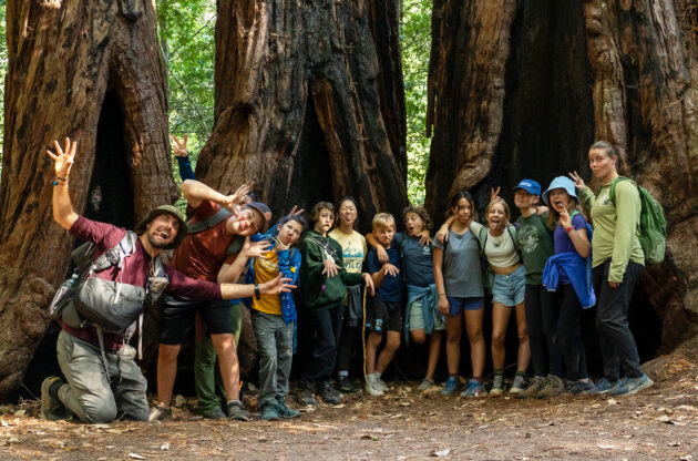 group of students making silly faces in a redwood forest.