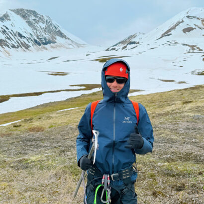 A teenager holding ice climbing tools in southeast Alaska smiling.