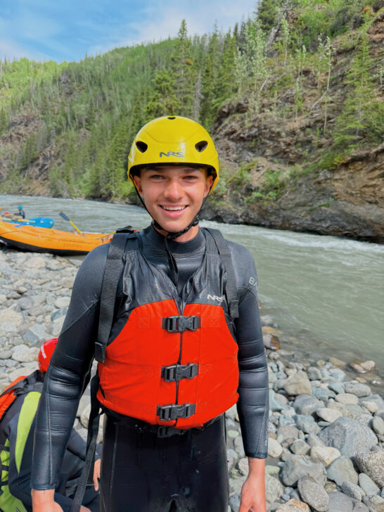 High school boy smiling with whitewater rafting gear on.