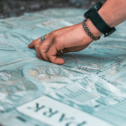 A person's hand pointing to a spot on a map.