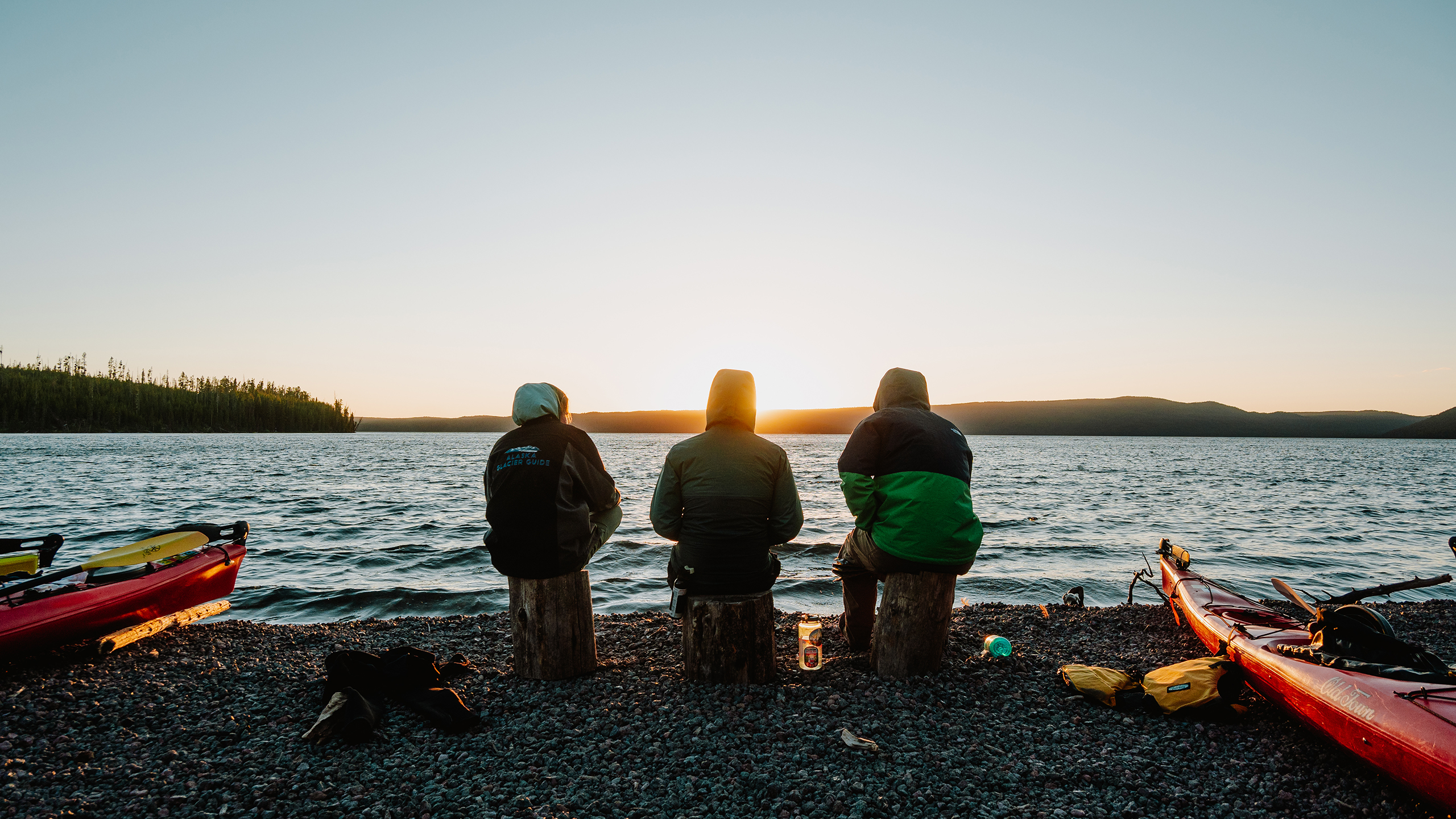 Three people watching the sunset on Yellowstone Lake.