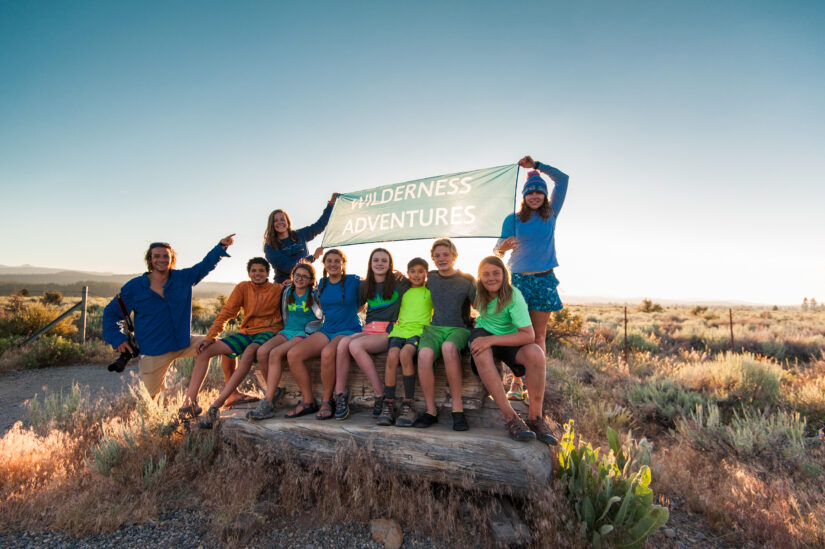Group of young students holding up a Wilderness Adventures banner with their Trip Leaders in California.